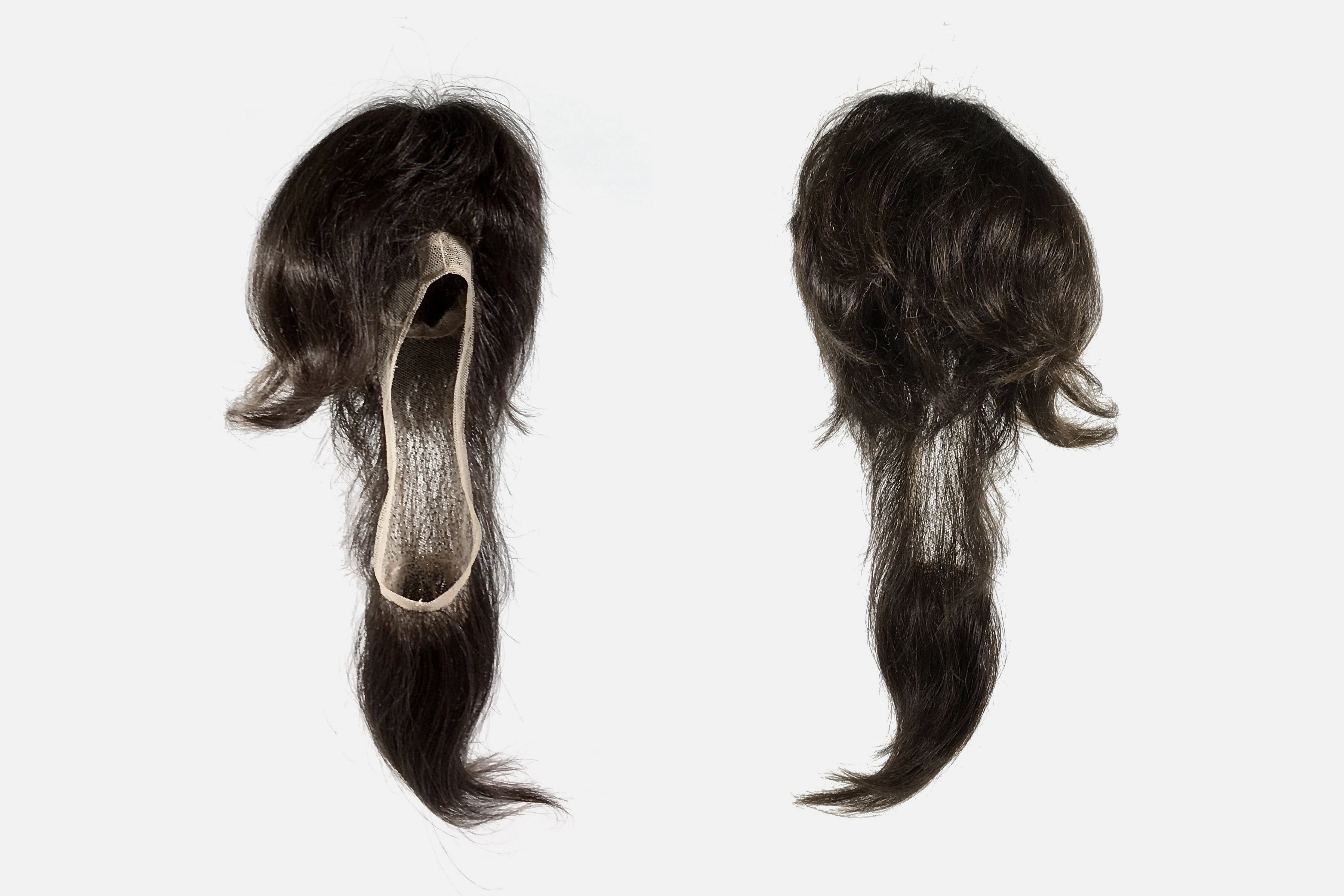 Two sculptural shoes with dark, curled hair, viewed from above.